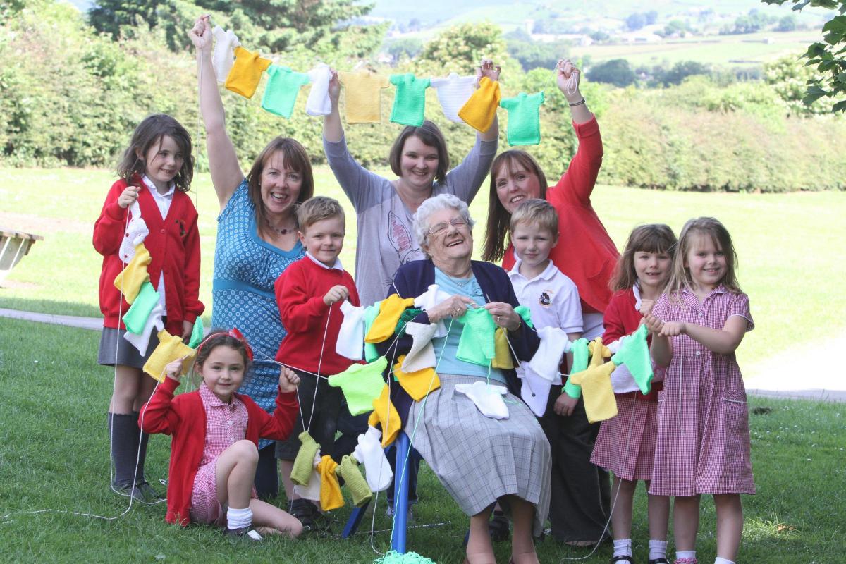 Cononley Primary School pupils, parents and staff knit  more than 200 Tour De France Jerseys which will be hung as bunting around the school. Grandma Joyce Wade with pupils and parents who knit some of the bunting.