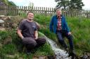 Jamie McEwan and Mark Corner by the water as it rejoins Backstone Gill after having gone through the new hydropower turbine.