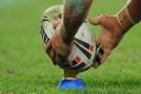 Man places rugby league ball on the kicking tee