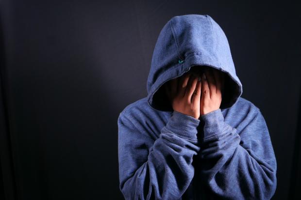 Craven Herald: A person touching their face wearing a blue hoodie. Credit: Canva