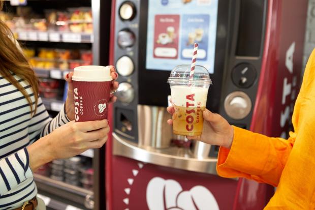 Craven Herald: One person holding a hot drink (left) and another person holding a cold drink (right) in front of a new Costa Express machine (Costa Coffee)