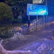 Flood water pouring through a garden wall in Coniston Cold. Video Thomas Beresford