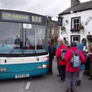A group of Friends of DalesBus members waiting to board DalesBus 874 outside the Bluebell in Kettlewell