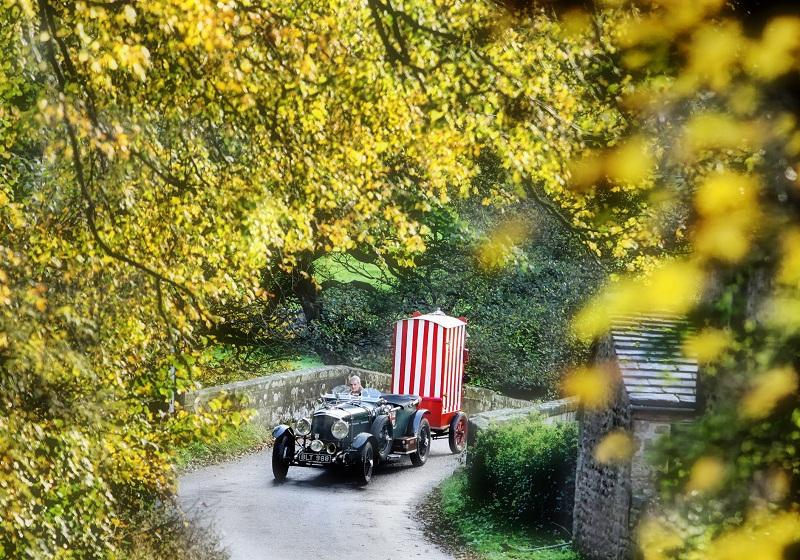 A canopy of colour frames a 1933 Bentley pulling a traditional Punch and Judy booth in this scene captured by Herald photographer Stephen Garnett near Hartlington, in Wharfedale