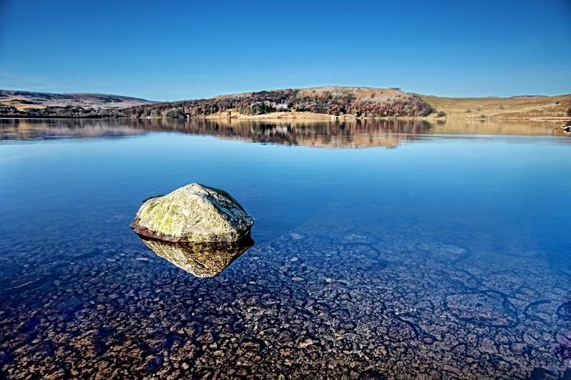 The flawless blue sky is reflected in the tranquil waters of Malham Tarn 