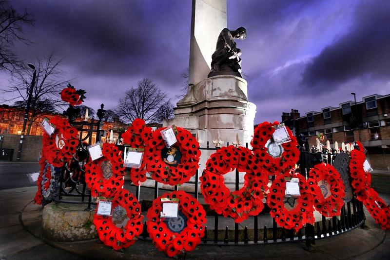 The  vibrant red wreaths stand out against the early evening twilight sky at Skipton Cenotaph.