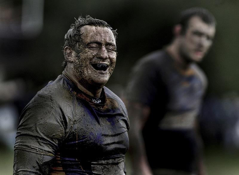 A prop forward breaks into laughter after being drenched in mud 