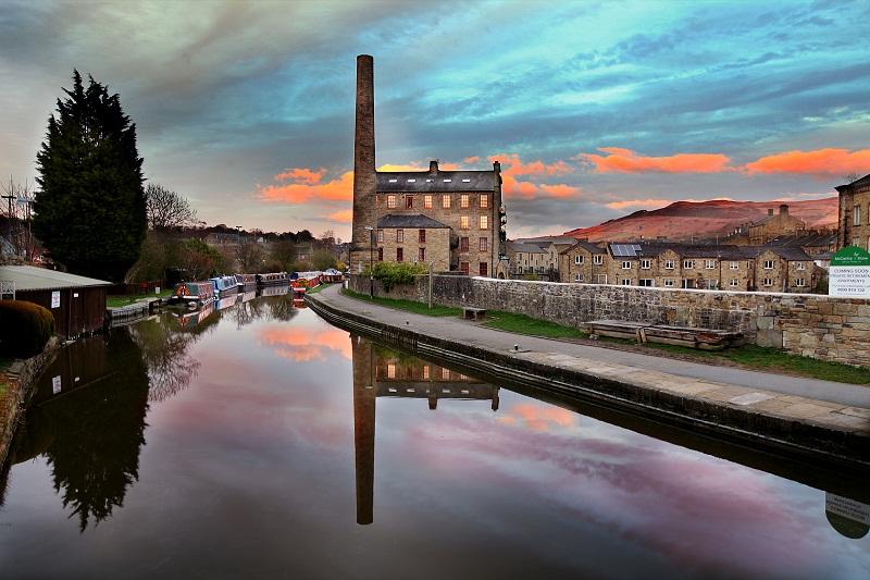 Standing proud as a former industrial workplace, Skipton’s Victoria Mill is reflected in the still canal waters during the late evening.