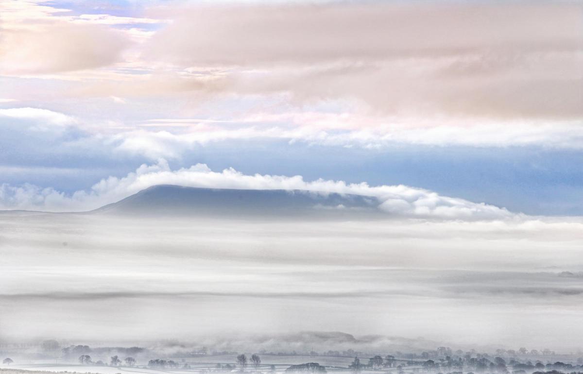 Layers of mist and cloud shroud the distinctly shaped Pendle Hill