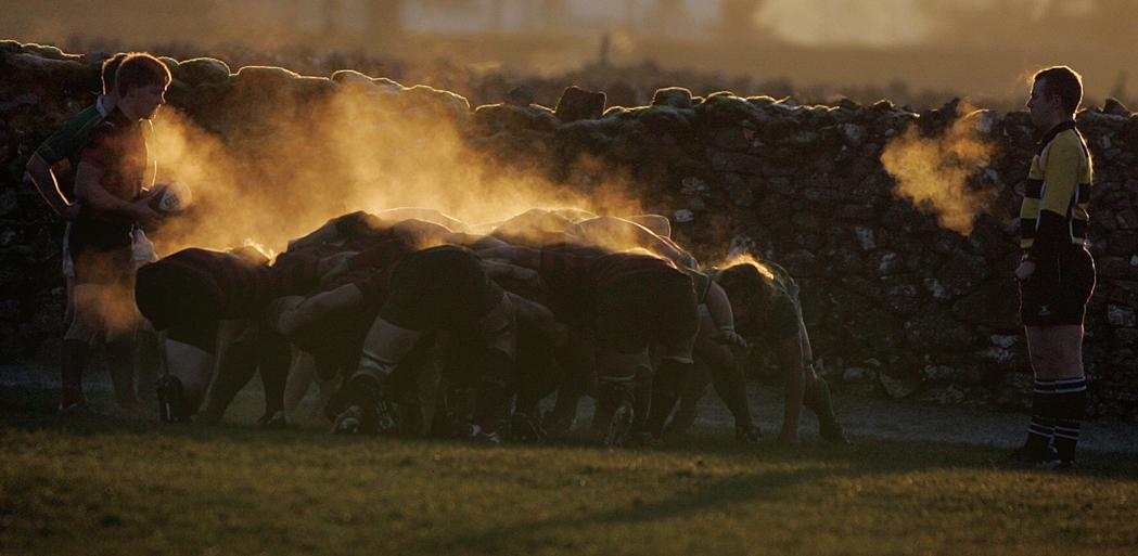 Steam rises as golden sunlight shines on this rugby scrum