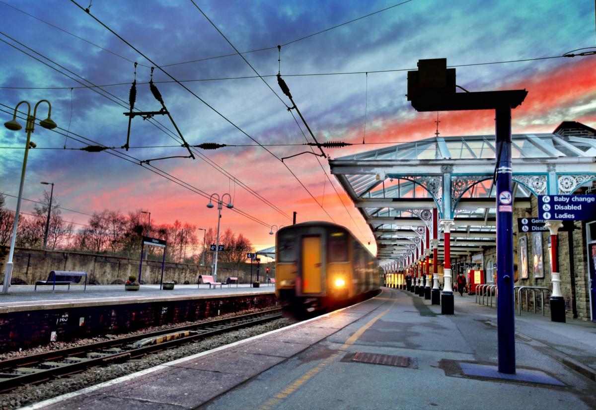 A Train sets of from Skipton Railway Station against the spectacular backdrop of a bright red evening sky , as the sun disappears in the west.