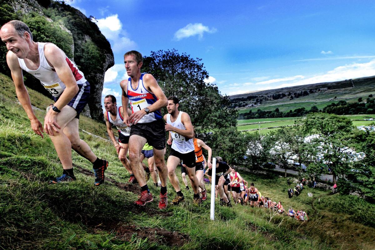 Garnetts Year -  As the lactic acid builds up in the leg muscles  a runner stoops forward to try  to ease the pain while ascending the slope in the famous Kilnsey Crag Race at Kilnsey Show.